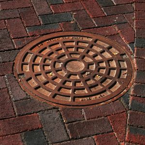 Manhole cover among brick