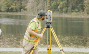 Surveyer using surveying equipent to survey a river